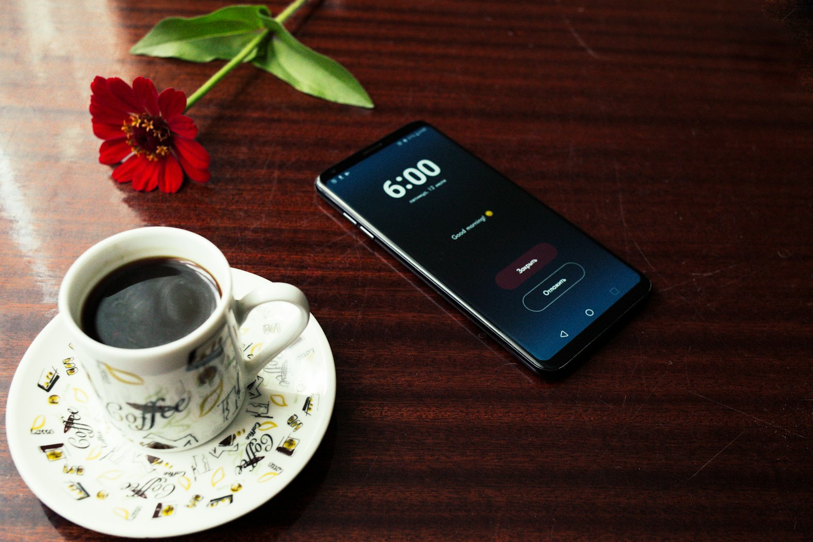 A smartphone beside a cup of coffee on a table in the morning