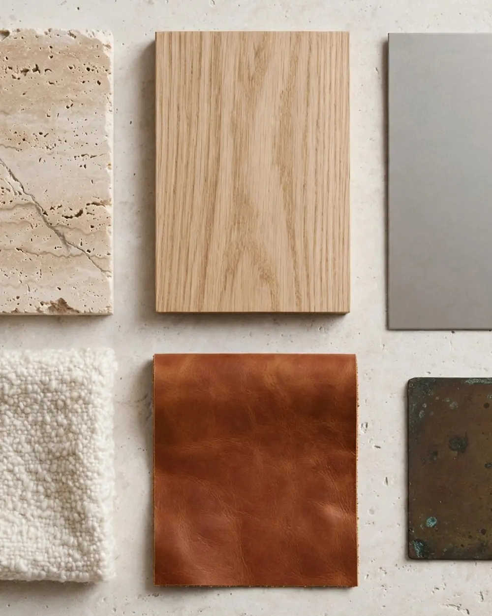 The material palette: travertine, white oak, bead-blasted steel, bouclé, cognac leather and aged bronze.